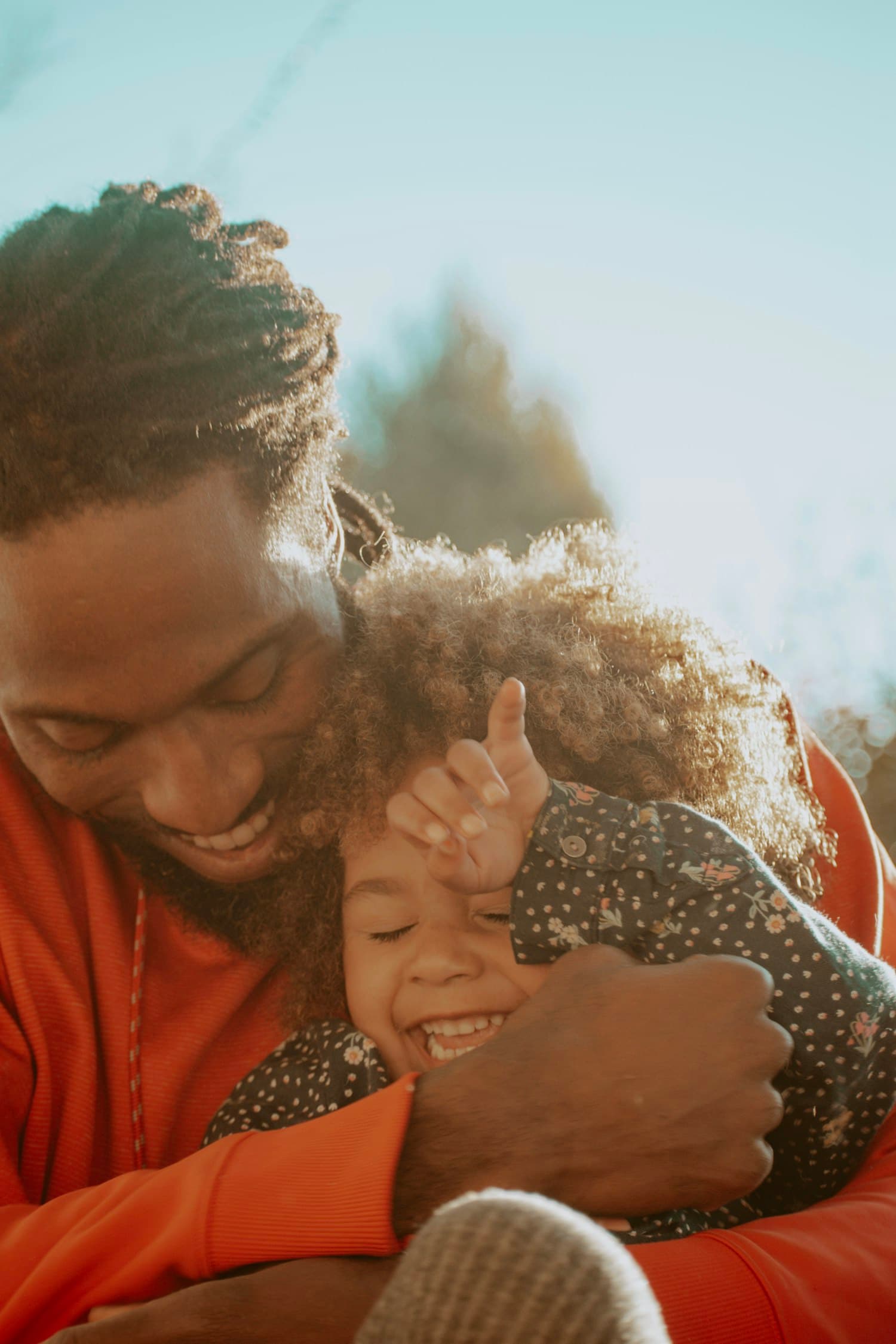 A father holding his laughing daughter in warm evening light